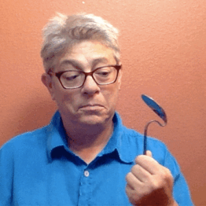 Miche in a blue shirt holding up a bent spoon.