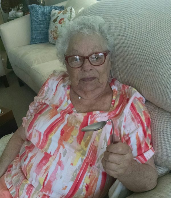 Miche's mom at age 82 sitting in a chair holding the spoon she just bent..